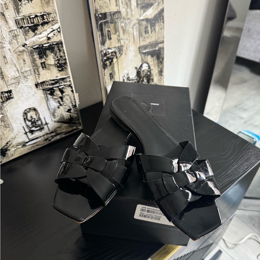 Saint Laurent Tribute Flat Sandal in black patent leather.